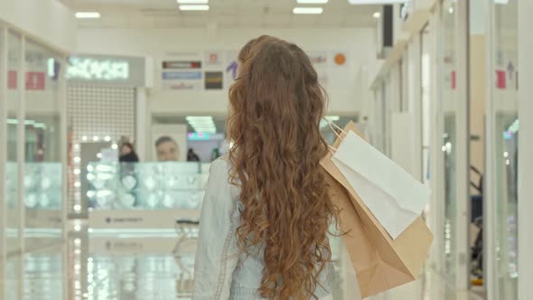 Rear View Shot of a Curly Haired Little Girl Looking at Clothing Stores at Shopping Mall