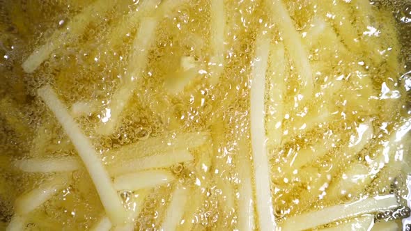 Slow motion of french fries in a pan with boiling oil
