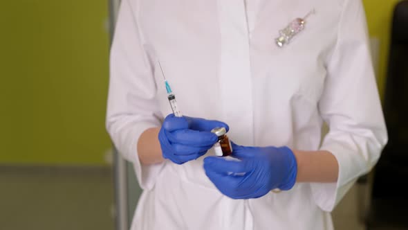Doctor in Gloves Taking Medicine From Vial with Syringe