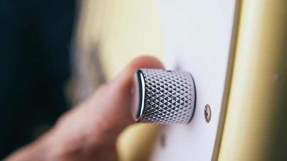 Finger Rotates Silver Volume Control Knob on Bass Guitar