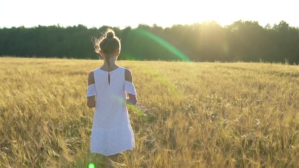 Adorable Preschooler Girl Walking Happily in Wheat Field on Warm and Sunny Summer Day