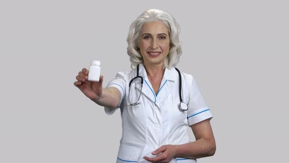 Old Female Doctor Recommends Bottle of Medicine