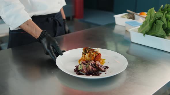 The chef gives the finished dish filet mignon and ratatouille in the restaurant kitchen