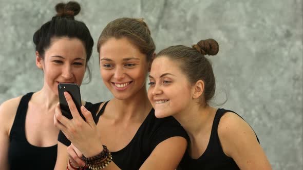 Three Young Women Browsing Internet Using Smartphone After Workout at Yoga Class