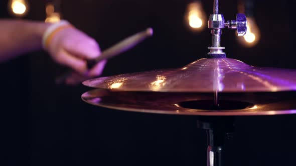 Drummer playing with sticks on hi hat close up in the dark.