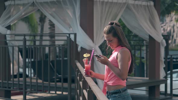 Girl with Loose Flowing Hair Looks at Phone Screen at Hotel