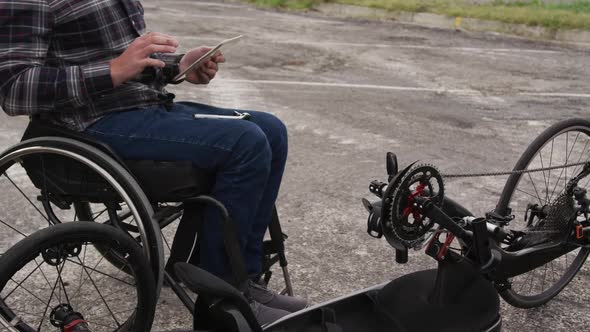 Disabled man on his touch pad after assembling parts of a bicycle
