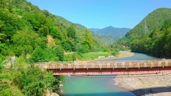 Aerial side view of a man crossing a bridge in Georgia over the Chorokhi River,