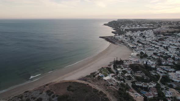 Small ocean waves gently unfolding on sand beach, Praia da Luz, Algarve. Scenic wide aerial