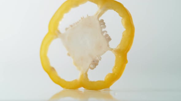 A sliced yellow pepper falling on water surface. Slow Motion.