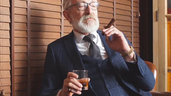 Fashionable Old Man Holding a Glass of Whiskey and Going To Smoke a Cigar