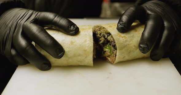 Ched cuts burrito in half and shows it. Mexican food.