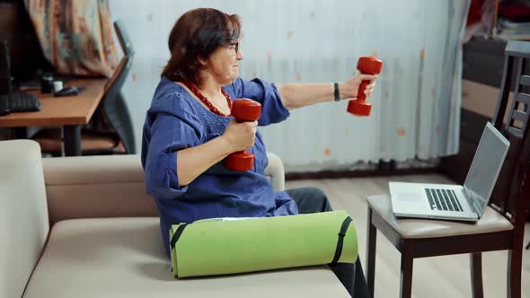 Mature Woman Training With Dumbbells On Home. Senior Woman Workout Weight Lifting.