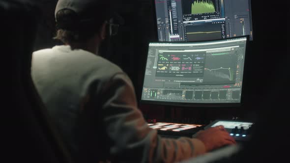 Sound Engineer Seen Seated From Behind Uses the Computer to Mix Audio Music