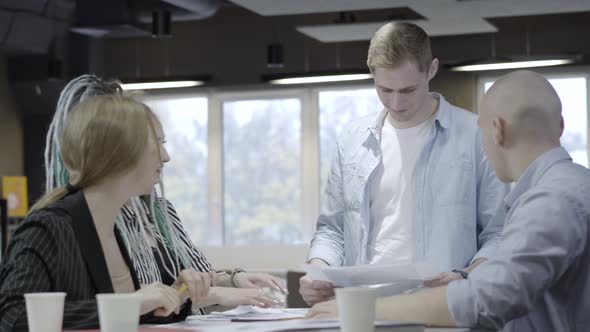 Group of Positive Young Caucasian Coworkers Talking and Laughing Sitting in Office