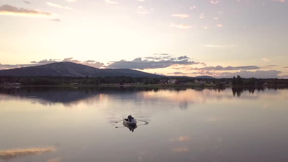 Group of friends rowing a boat in a calm lake during midnight sun in Lapland.