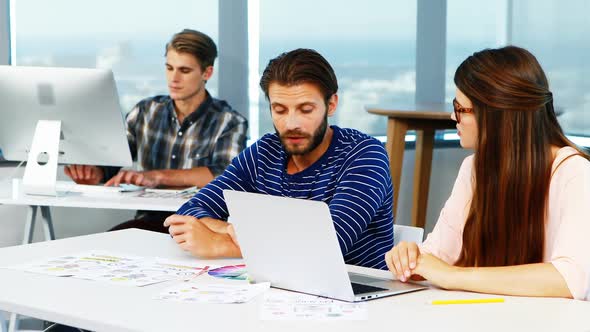 Graphic designers discussing over laptop at desk