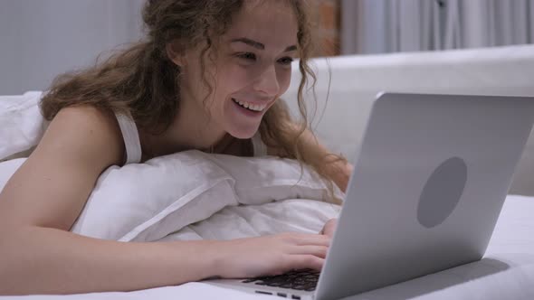 Online Video Chat on Laptop by Female in Bed, Headphone