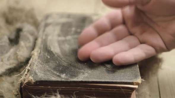 Cleaning dust of a dirty musty old book to open pages