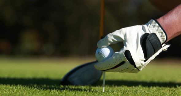 Golfer placing golf ball on tee