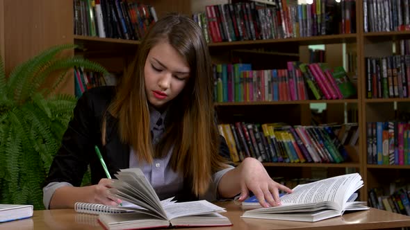 Portrait of Clever Student with Open Book Reading It in College Library