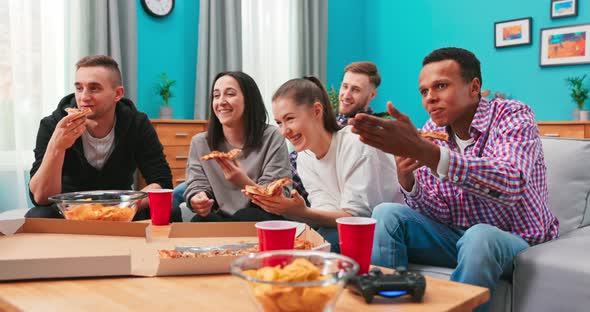 Young People Cheerful Men and Women are Eating Cheesy Pizza Chatting Relaxing During Indoor Party