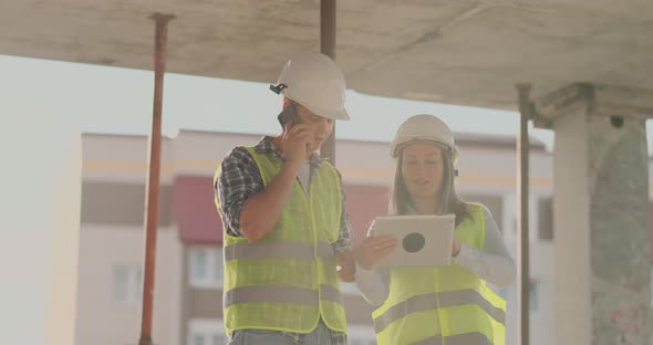 Supervisor of a Building Under Construction Man Discussing with Engineer Designer Woman the Progress