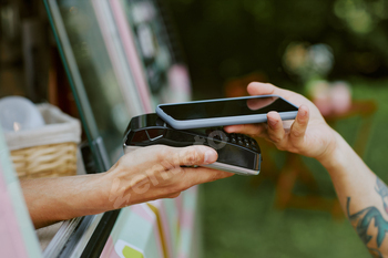 Hands Holding Payment Terminal and Smartphone