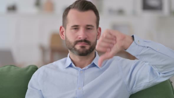 Young Man with Thumbs Down at Home
