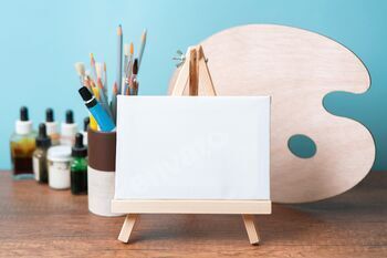 small wooden easel with blank canvas on wooden table