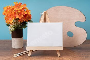 small wooden easel with blank canvas on wooden table