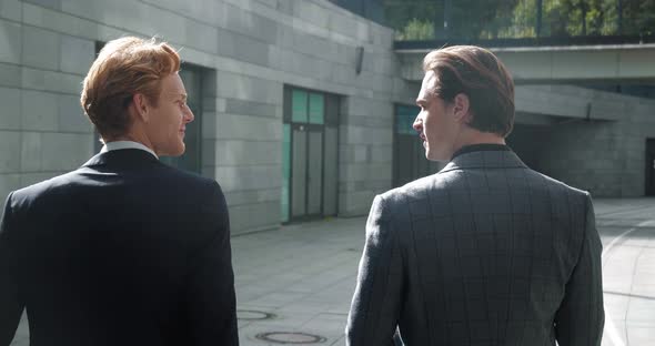 Back View of Two Businessmen Discussing Deals While Walking Outside Office at Break