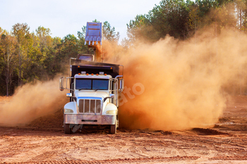 Construction truck at work creating dust in construction area during land removal