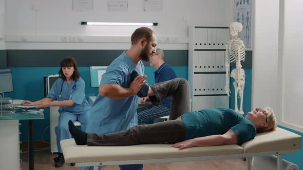 Elder Person Raising Legs to Stretch Muscles in Osteopathy Cabinet