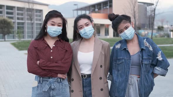 Portrait of a group of Asian female friends using a face mask while standing outdoors