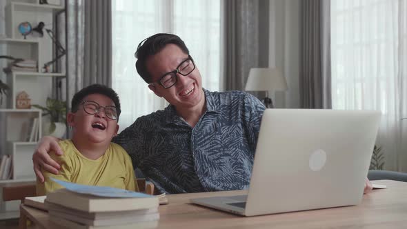 Happy Asian Father And His Son Having Video Call In Living Room