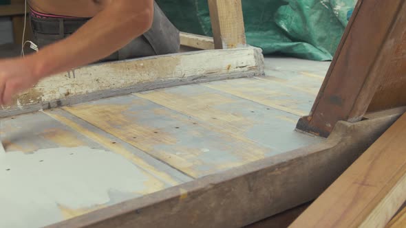 Man painting sanded teak deck planking with aluminium based wood primer