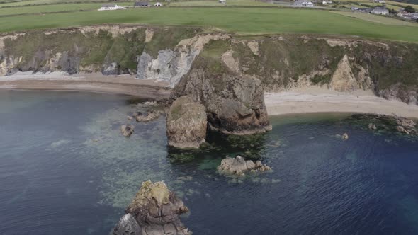 Aerial orbits headland jutting into sea on south coast of Ireland