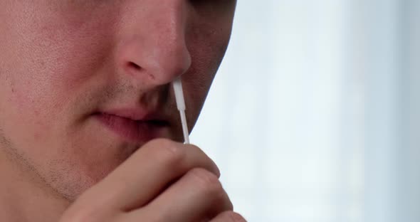 Man using nasal swab to take rapid self test for Covid-19.