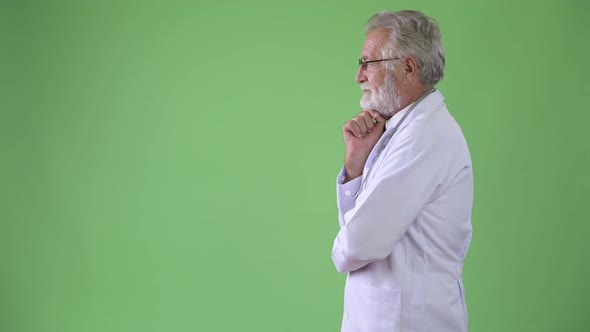 Handsome Senior Bearded Man Doctor Against Green Background