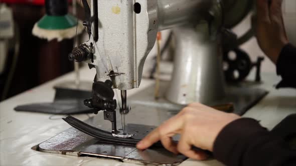 Old Master Is Making Stitches By Vintage Industrial Sewing Machine on a Belt