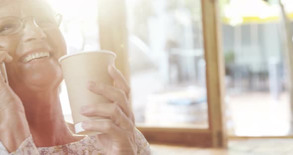 Happy Senior Woman Talking Over the Phone While Having Coffee