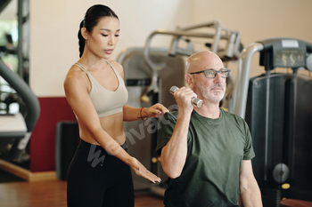 Personal Trainer Assisting Senior Client in Gym