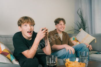 Excited engaged Teenager boys with a gaming controller emotionally screaming in gaming process.