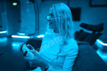 Young woman enjoying video games in a vibrant blue-lit gaming room