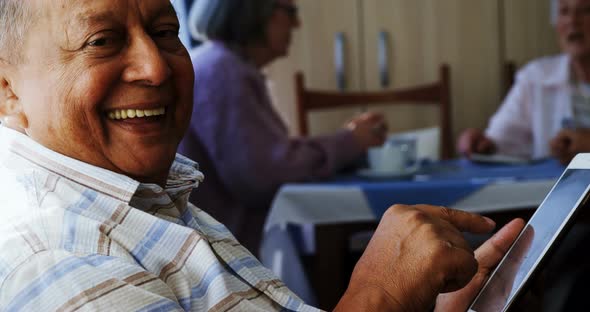 Senior man using digital tablet with his friends sitting in background 4k