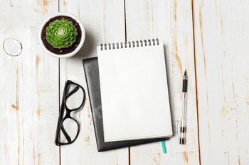 Succulent and Notebook paper in pot on table