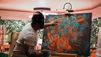 Painter applies watercolor paints to a canvas with his fingers