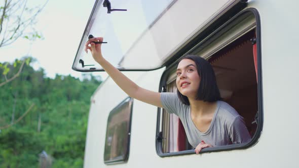 Asian young girl feeling relax on camper van open window in the morning with happiness and smile.