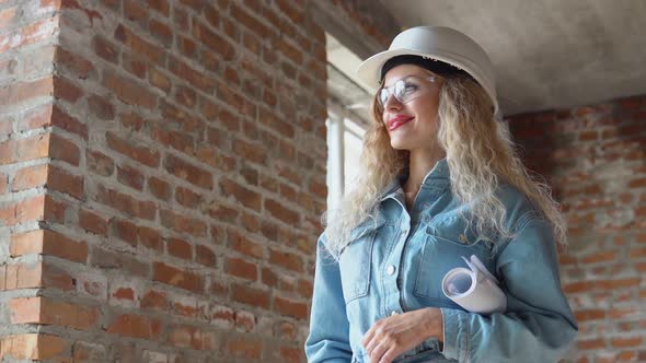 Female Architect Holding an Architectural Construction Plan While on the Construction Site